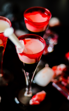 Creepy Halloween party cocktails with syringes of grenadine syrup as blood, shot drinks at party, scary barの写真素材