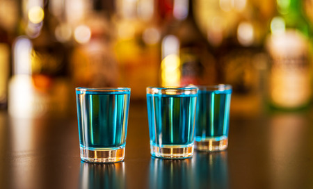 Popular blue drink shot kamikaze on the background of the bar with bottles, a refreshing drink, party nightの写真素材