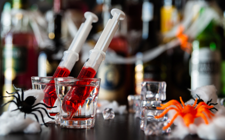 Creepy Halloween party cocktails with spiders and syringes of grenadine syrup as blood, shot drinks at party, scary barの写真素材