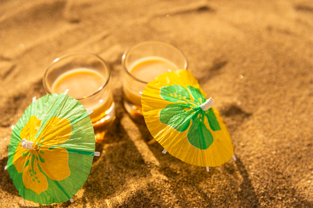 Colorful shots drinks on a sandy beach with umbrellas for drinks, summer relaxの写真素材