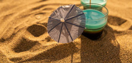 Colorful shots drinks on a sandy beach with umbrellas for drinks, summer relaxの写真素材