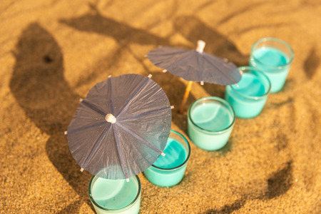 Colorful shots drinks on a sandy beach with umbrellas for drinks, summer relaxの写真素材