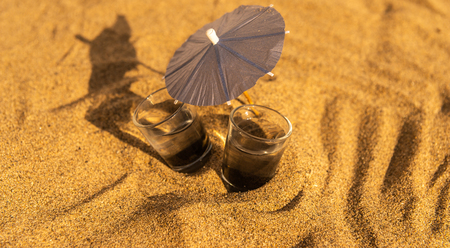 Colorful shots drinks on a sandy beach with umbrellas for drinks, summer relaxの写真素材