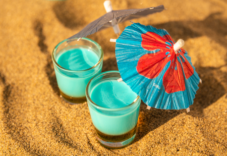 Colorful shots drinks on a sandy beach with umbrellas for drinks, summer relaxの写真素材