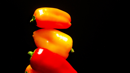 red and yellow peppers on a black background, healthy and delicious vegetarian products, vegetablesの写真素材