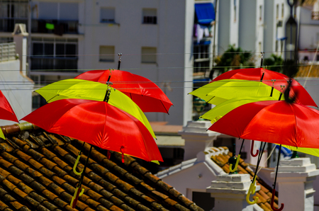 Colourful umbrellas urban street decoration. Hanging colorful umbrellas over blue sky, tourist attraction, sunny dayの写真素材
