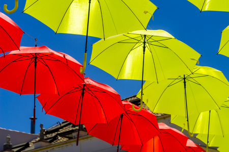 Colourful umbrellas urban street decoration. Hanging colorful umbrellas over blue sky, tourist attraction, sunny dayの写真素材