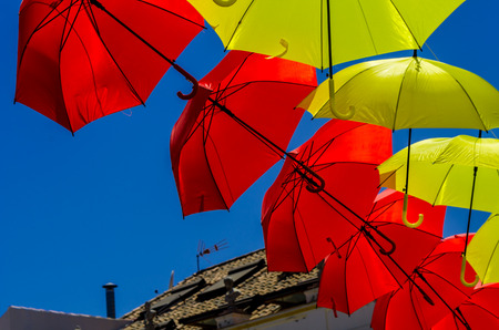 Colourful umbrellas urban street decoration. Hanging colorful umbrellas over blue sky, tourist attraction, sunny dayの写真素材