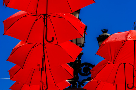 Colourful umbrellas urban street decoration. Hanging colorful umbrellas over blue sky, tourist attraction, sunny dayの写真素材