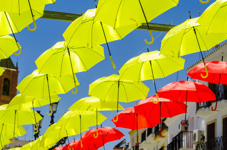 Colourful umbrellas urban street decoration. Hanging colorful umbrellas over blue sky, tourist attraction, sunny dayの写真素材