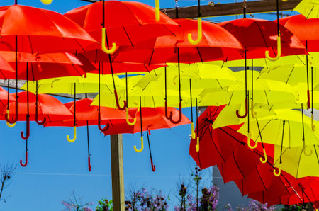 Colourful umbrellas urban street decoration. Hanging colorful umbrellas over blue sky, tourist attraction, sunny dayの写真素材