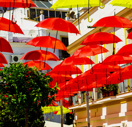 Colourful umbrellas urban street decoration. Hanging colorful umbrellas over blue sky, tourist attraction, sunny dayの写真素材
