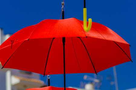 Colourful umbrellas urban street decoration. Hanging colorful umbrellas over blue sky, tourist attraction, sunny dayの写真素材