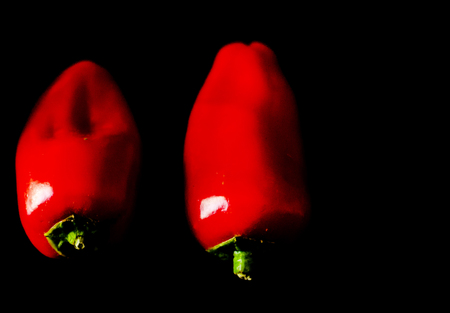 Red and yellow peppers on a black background, healthy and delicious vegetarian products, vegetablesの写真素材