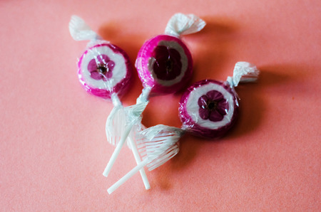 Colorful fruit lollipops on a pink background, unhealthy but delicious snack for children, sweetsの写真素材