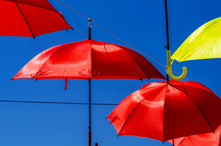 Colorful umbrellas urban street decoration. Hanging colorful umbrellas over blue sky, tourist attraction, sunny dayの写真素材