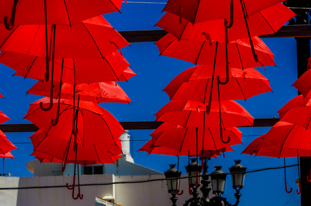 Colorful umbrellas urban street decoration. Hanging colorful umbrellas over blue sky, tourist attraction, sunny dayの写真素材