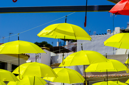 Colorful umbrellas urban street decoration. Hanging colorful umbrellas over blue sky, tourist attraction, sunny dayの写真素材