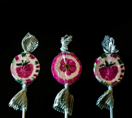 Colorful fruit lollipops on a black background, unhealthy but delicious snack for children, sweetsの写真素材