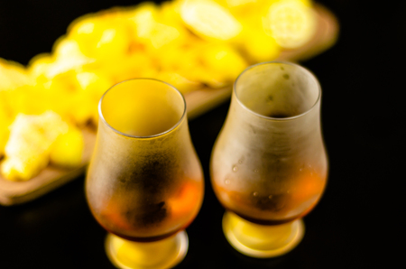 Glasses of whiskey with ice cubes and salty snacks on the background of the bar, party timeの写真素材