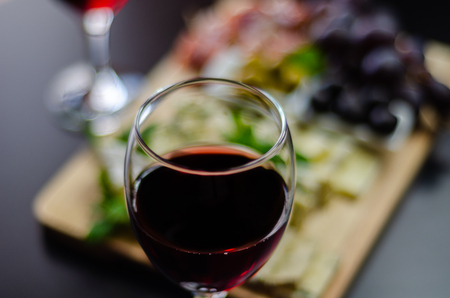 Red wine and set of different cheeses on a wooden board, delicious snack, healthy and exclusive foodの写真素材