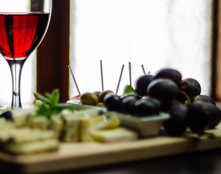 Red wine and set of different cheeses on a wooden board, delicious snack, healthy and exclusive foodの写真素材