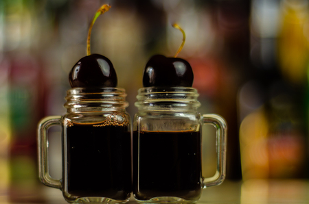 Cherry liqueur and juicy ripe cherries on the table in  the bar, an elegant serving of sweet drink in the restaurant, a traditional drinkの写真素材