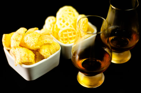 Glasses of whiskey with salty snacks on the background of the bar, party timeの写真素材