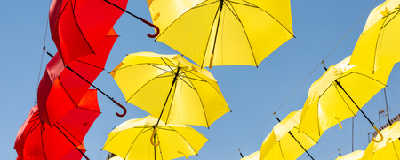 Colourful umbrellas urban street decoration. Hanging colorful umbrellas over blue sky, tourist attraction, sunny dayの写真素材