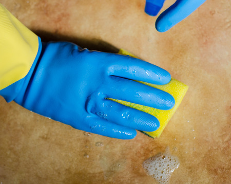 Hands in rubber gloves cleaning the surfaces of ceramic tiles, safe and hygienic cleaning, keeping the house cleanの写真素材