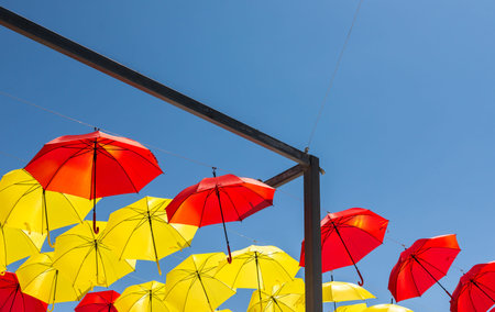 Colourful umbrellas urban street decoration. Hanging colorful umbrellas over blue sky, tourist attraction, sunny dayの写真素材