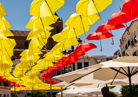 Colourful umbrellas urban street decoration. Hanging colorful umbrellas over blue sky, tourist attraction, sunny dayの写真素材