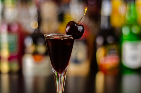 Cherry liqueur and juicy ripe cherries on the table in  the bar, an elegant serving of sweet drink in the restaurant, a traditional drinkの写真素材
