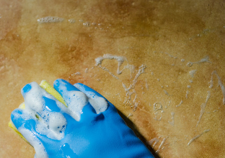 Hand in rubber gloves cleaning the surfaces of ceramic tiles, safe and hygienic cleaning, keeping the house cleanの写真素材