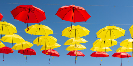 Colourful umbrellas urban street decoration. Hanging colorful umbrellas over blue sky, tourist attraction, sunny dayの写真素材