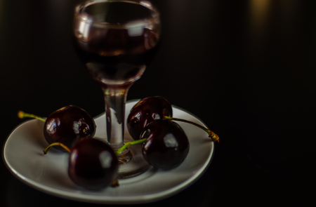 Cherry liqueur and juicy ripe cherries on the table in  the bar, an elegant serving of sweet drink in the restaurant, a traditional drinkの写真素材