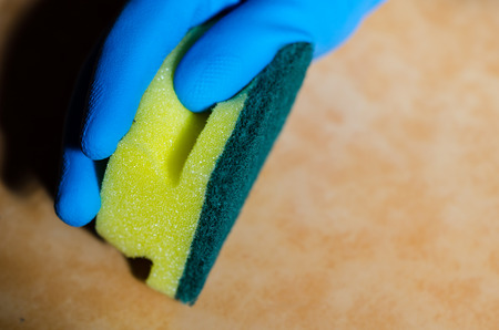 Hand in rubber gloves cleaning the surfaces of ceramic tiles, safe and hygienic cleaning, keeping the house cleanの写真素材