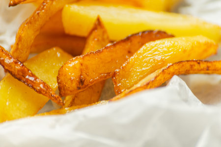 Closeup of golden fries prepared from fresh potatoes, greasy but delicious food, unhealthy