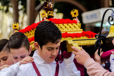 Procession of children starting the holy week.Children in the procession wear platforms with images...