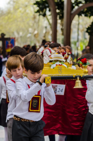 Procession of children starting the holy week.Children in the procession wear platforms with images...