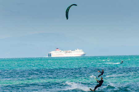 MALAGA, SPAIN - MAY 25, 2018 People practicing active sport, wave riding using power kite in a windy bayのeditorial素材