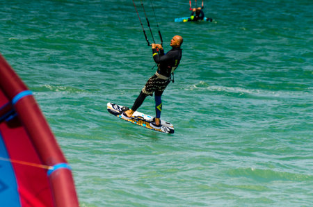 MALAGA, SPAIN - MAY 25, 2018 People practicing active sport, wave riding using power kite in a windy bayのeditorial素材