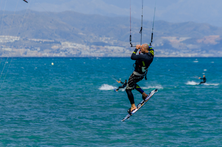 MALAGA, SPAIN - MAY 25, 2018 People practicing active sport, wave riding using power kite in a windy bayのeditorial素材