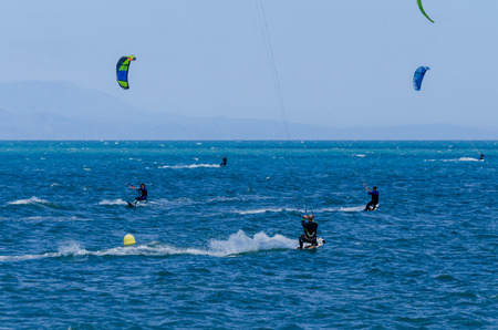 MALAGA, SPAIN - MAY 25, 2018 People practicing active sport, wave riding using power kite in a windy bayのeditorial素材