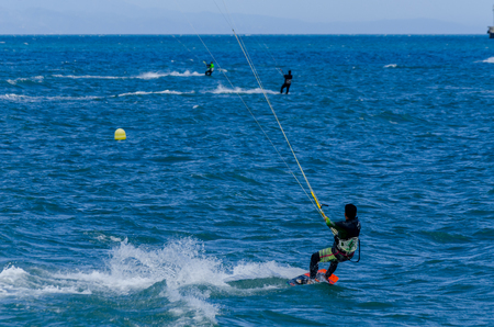 MALAGA, SPAIN - MAY 25, 2018 People practicing active sport, wave riding using power kite in a windy bayのeditorial素材