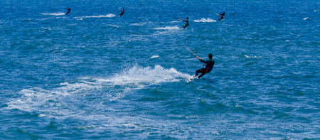 MALAGA, SPAIN - MAY 25, 2018 People practicing active sport, wave riding using power kite in a windy bayのeditorial素材