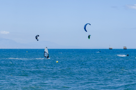 MALAGA, SPAIN - MAY 25, 2018 People practicing active sport, wave riding using power kite in a windy bayのeditorial素材