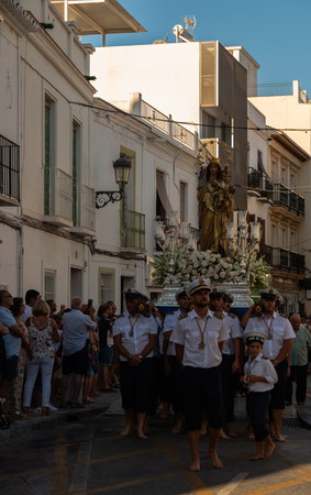 NERJA, SPAIN - JULY 16, 2018 people participating in the celebration of the Catholic ceremony of transferring the holy figure in Spain. The 'Virgen del Carmen' is the patron saint and protector of fishermen and sailorsのeditorial素材