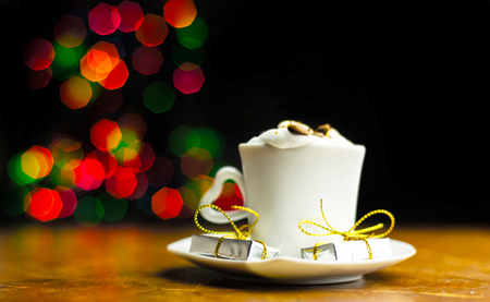 Christmas coffee with whipped cream and a small gift on the background bokeh lights, xmasの写真素材