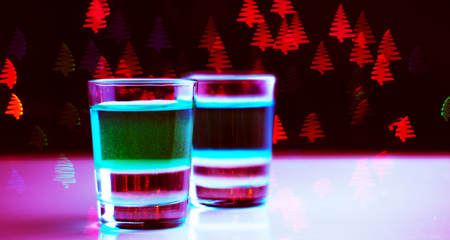 Drink shot in a shot glass on a Christmas tree-shaped bokeh background, Christmas decoration on the bar, xmas partyの写真素材